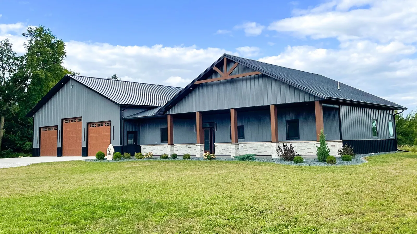 Barndominium with timber posts, stone wainscot and a shop bay